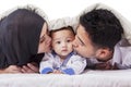Young parents kissing their baby under blanket Royalty Free Stock Photo