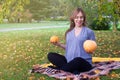 Portrait of happy young pregnant model sitting with crossed legs on grass lawn and looking at her belly with gentle smile. Future