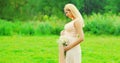 Portrait of happy young pregnant woman with flowers in sunny summer day Royalty Free Stock Photo