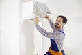 Portrait of happy young repairman using screwdriver while fixing air conditioner on wall