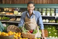 Portrait of a happy young salesman with vegetable basket in supermarket