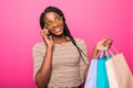 Portrait of happy young with shopping bags woman talking on cellphone on pink background Royalty Free Stock Photo