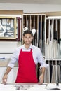 Portrait of a happy young skilled worker standing with meter stick in workshop Royalty Free Stock Photo