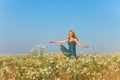 Portrait happy of the young slender blonde in blue jeans a sundress in the field of camomiles in a sunny day Royalty Free Stock Photo