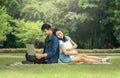 Portrait of a happy young students sitting on the park and using laptop