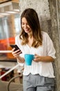 Portrait of a happy young success woman using smartphone and drinking coffee in break Royalty Free Stock Photo