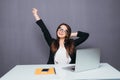 Portrait of happy young successful businesswoman celebrate something with arms up. Happy woman sit at office and look at laptop. P Royalty Free Stock Photo