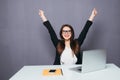 Portrait of happy young successful businesswoman celebrate something with arms up. Happy woman sit at office and look at laptop. P Royalty Free Stock Photo