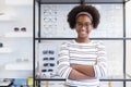 Portrait happy young woman African American afro hair smile wear spectacles crossed arm standing at in optical shop.