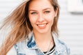 Portrait of a happy young woman with amazing blue eyes with a wonderful smile with natural make-up in a trendy denim jacket