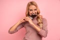Portrait of a happy young woman biting chocolate bar isolated over pink background Royalty Free Stock Photo