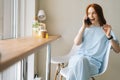 Portrait of happy young woman in good mood talking on mobile phone sitting in cozy cafe by window. Royalty Free Stock Photo