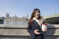Portrait of happy young woman holding cell phone and disposable cup against Big Ben at London, England, UK Royalty Free Stock Photo