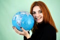 Portrait of a happy young woman holding geographic globe of the world in her hands. Travel destination and planet protection Royalty Free Stock Photo