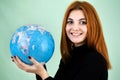 Portrait of a happy young woman holding geographic globe of the world in her hands. Travel destination and planet protection Royalty Free Stock Photo