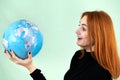 Portrait of a happy young woman holding geographic globe of the world in her hands. Travel destination and planet protection Royalty Free Stock Photo