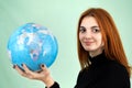 Portrait of a happy young woman holding geographic globe of the world in her hands. Travel destination and planet protection