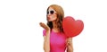 Happy young woman holding red heart shaped balloon and blowing lips sending sweet air kiss isolated on a white Royalty Free Stock Photo