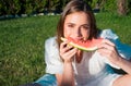 Portrait happy young woman is holding slice of watermelon. Beautiful young woman with watermelon in park on sunny day. Royalty Free Stock Photo