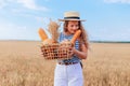 Portrait of happy young woman holding a wicker basket in her hands and smelling excited the fresh baked bread, with a Royalty Free Stock Photo