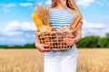 Portrait of happy young woman holding a wicker basket in her hands, with a wheat field in the background Royalty Free Stock Photo