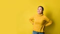 Portrait of happy young woman laughing against yellow wall. Photo of positive excited. person in sweater rejoices on yellow studio