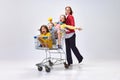 Portrait of happy young woman, mother going shopping with her little kids, children sitting in shopping trolley against Royalty Free Stock Photo