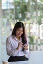 Happy young woman office worker sitting in office and using mobile phone. Royalty Free Stock Photo