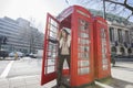 Portrait of happy young woman opening door of telephone booth at London, England, UK