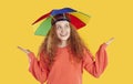 Portrait of happy young woman with rainbow hat umbrella on her head that protects from rain or sun. Royalty Free Stock Photo