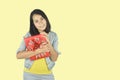 Portrait of happy young woman red gift box hugging gesture on yellow background. Present for birthday, valentine day, Christmas, Royalty Free Stock Photo