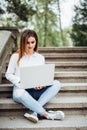 Portrait of a happy young woman sitting on the city stairs and using laptop computer outdoors Royalty Free Stock Photo