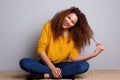 Happy young woman sitting on floor and laughing by gray wall Royalty Free Stock Photo