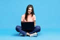 Portrait of happy young woman sitting on floor with legs crossed working on laptop Royalty Free Stock Photo