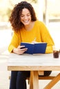 Happy young woman sitting at table writing notes in book Royalty Free Stock Photo