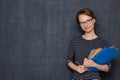 Portrait of happy young woman smiling and holding folders and pen Royalty Free Stock Photo