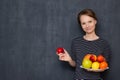 Portrait of happy young woman smiling and holding plate of fruits Royalty Free Stock Photo