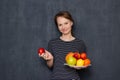 Portrait of happy young woman smiling and holding plate of fruits Royalty Free Stock Photo