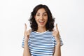 Portrait of happy young woman smiling white teeth, pointing fingers up, showing advertisement, telling about promo Royalty Free Stock Photo