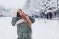 Portrait of happy young woman in snowy winter park wearing warm knitted clothes and red festive lipstick. Royalty Free Stock Photo