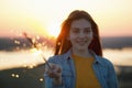 Portrait of happy young woman with sparkler in hand in summer evening Royalty Free Stock Photo