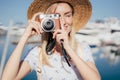 Happy young woman traveler photographer in straw hat taking photo on camera on sunny summer day. Royalty Free Stock Photo