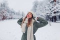 Portrait of happy young woman in snowy winter park wearing warm knitted clothes and red festive lipstick Royalty Free Stock Photo