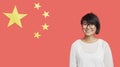Portrait of happy young woman wearing eyeglasses against Chinese flag