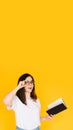 Portrait of a happy young woman wearing glasses and white T-shirt, immersed in reading a book with an open mouth Royalty Free Stock Photo