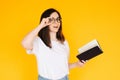 Portrait of a happy young woman wearing glasses and white T-shirt, immersed in reading a book with an open mouth, isolated on a Royalty Free Stock Photo