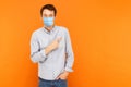 Portrait of happy young worker man with surgical medical mask standing, pointing and showing background empty copy space and Royalty Free Stock Photo