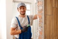 Portrait of hard working handyman or craftsman smiling at camera while filling the wall, preparing it for painting