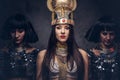 Portrait of haughty Egyptian queen in an ancient pharaoh costume with two concubines. Royalty Free Stock Photo