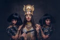 Portrait of haughty Egyptian queen in an ancient pharaoh costume with two concubines. Royalty Free Stock Photo